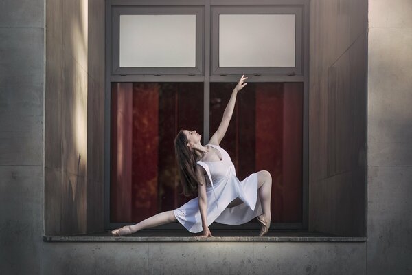 The pose of a ballerina on the background of a window
