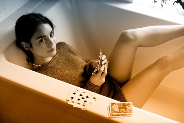 Лежащая девушка в ванне с картами