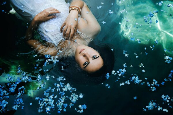 The girl is lying in the water in a dress