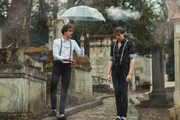 Deux hommes sous la pluie, l un sous un parapluie