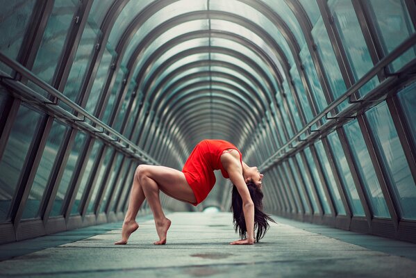 La jeune fille gymnaste dans le rouge avec une belle forme et jambes minces