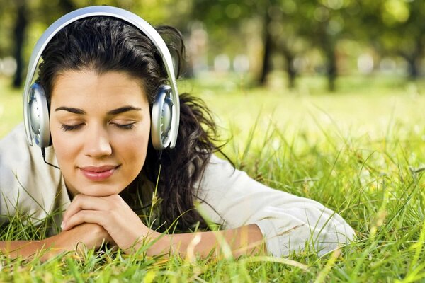 Mädchen, das sich auf dem Rasen ausruht und Musik hört