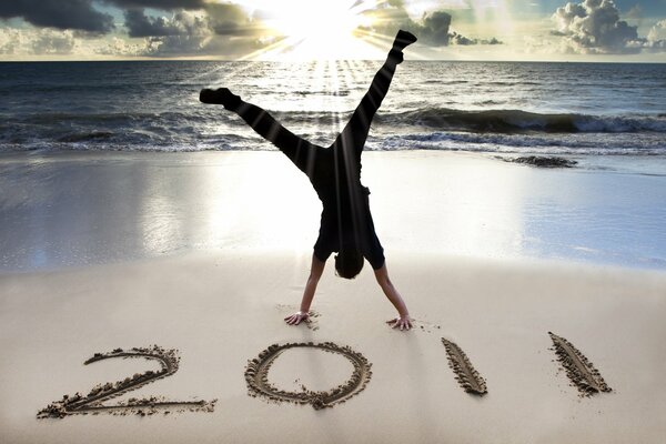 A man stands on his hands on the beach