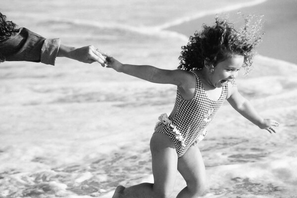 Curly-haired girl runs to swim in the sea