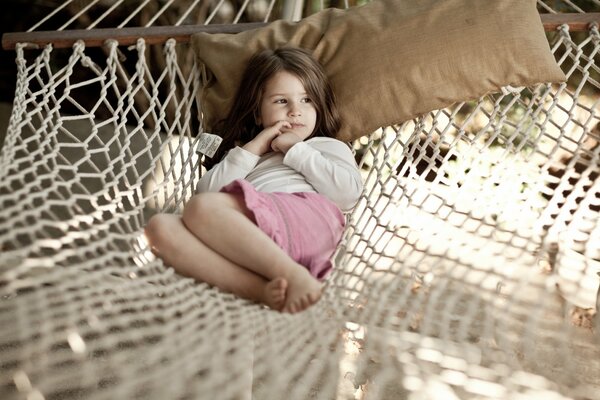 A little girl is lying in a hammock