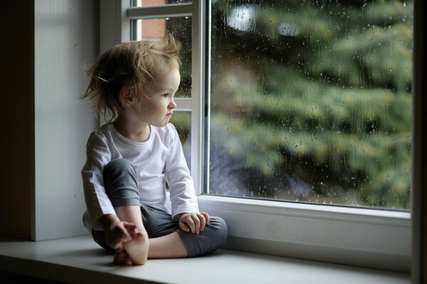 A child looking out the window in the rain