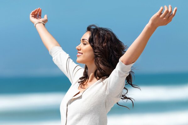 Feliz chica sonriente contra el cielo y el mar