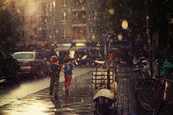 Kinder laufen im Regen über den Bürgersteig
