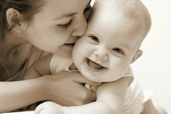 Maman embrasse bébé souriant