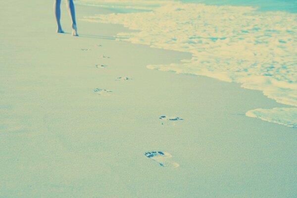 Fille marchant sur le sable laissant des traces