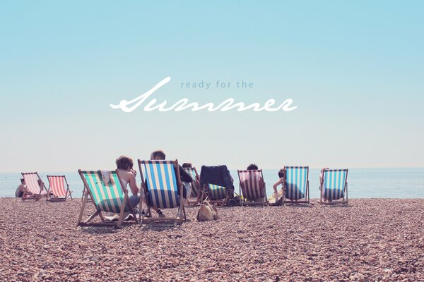 Les vacanciers dans les chaises longues sur la plage de galets