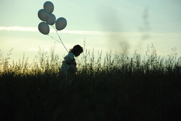 A girl with a balloon and against the background of the evening sky