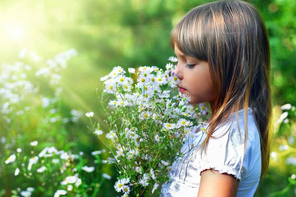 A girl sniffs a bouquet of daisies