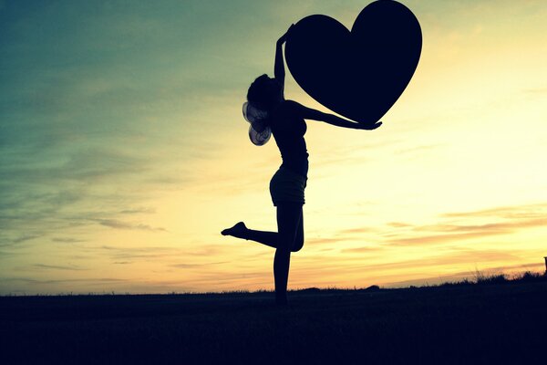 Photo of a winged girl at sunset with a heart