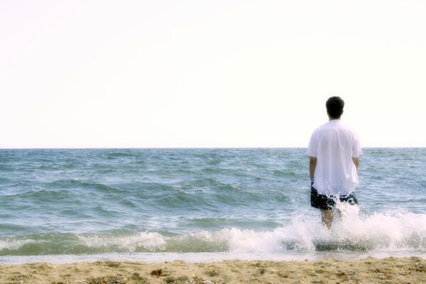 A man on the seashore in the spray of waves