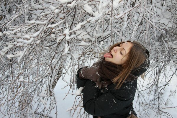 Chica atrapa la nieve con la lengua