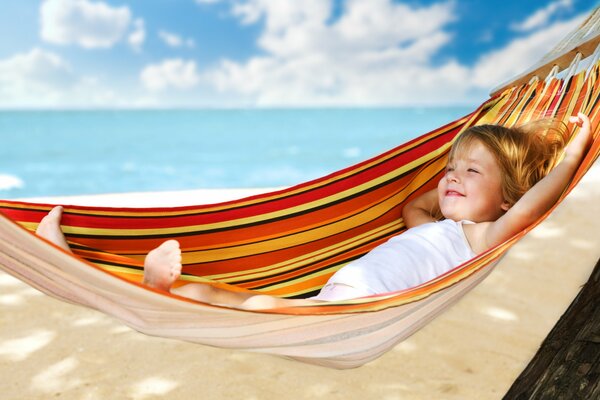 A child in a hammock on the background of the blue sea