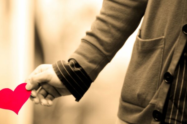 Photo of a paper heart in the hands of a guy