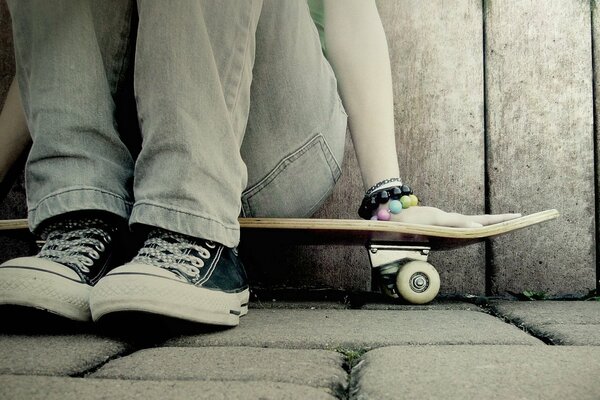 Una ragazza in scarpe da ginnastica si siede su uno skateboard