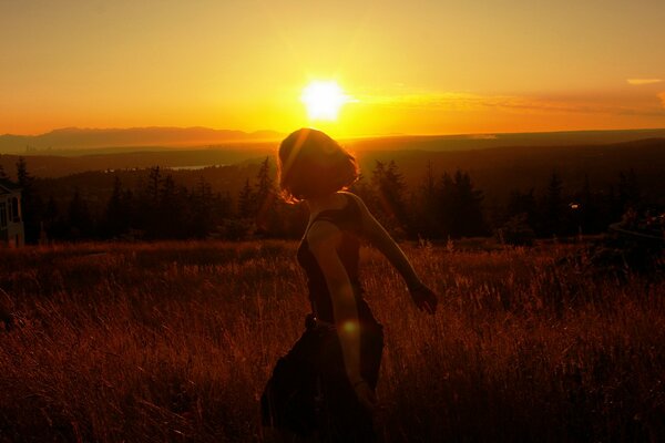 Fille dans le champ. Coucher de soleil sur la nature