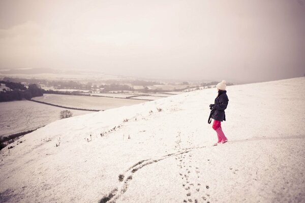 A girl with a camera in the distance on a snowy hill