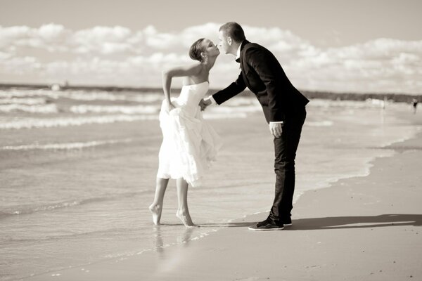 The bride and groom kiss by the sea