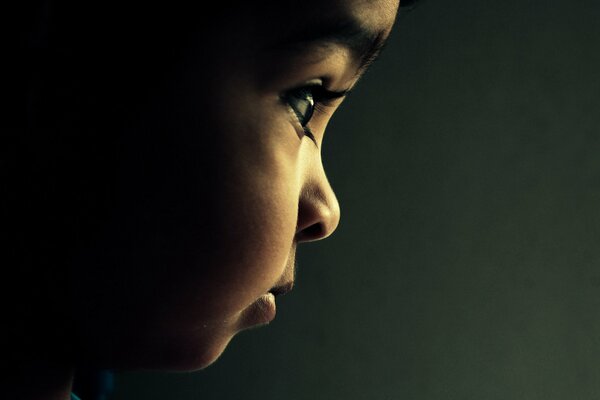 Profile of the child s face on a dark background