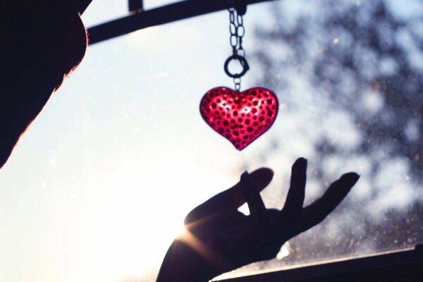 Keychain in the form of a red heart in your hand