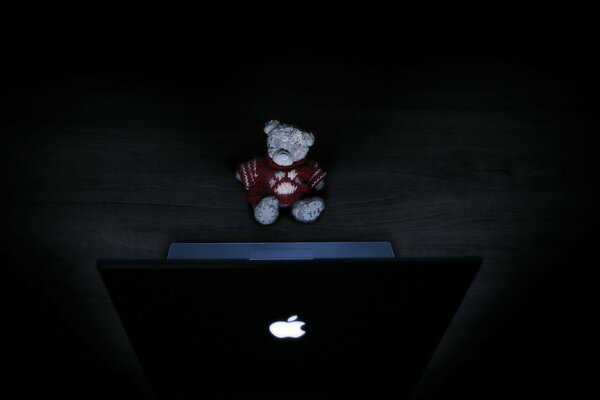 A bear toy in front of a laptop