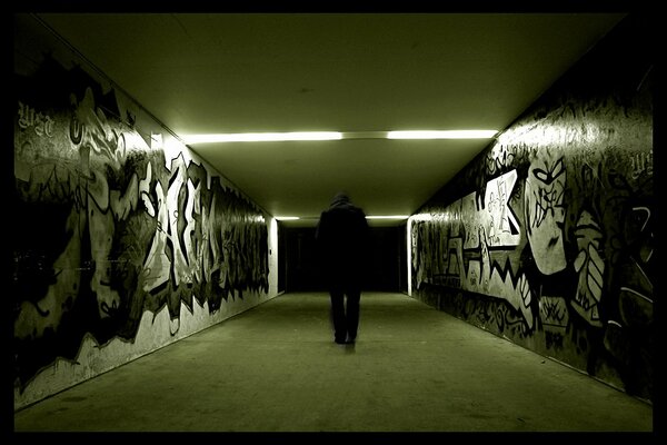 Foto cupa di un uomo in una metropolitana con graffiti