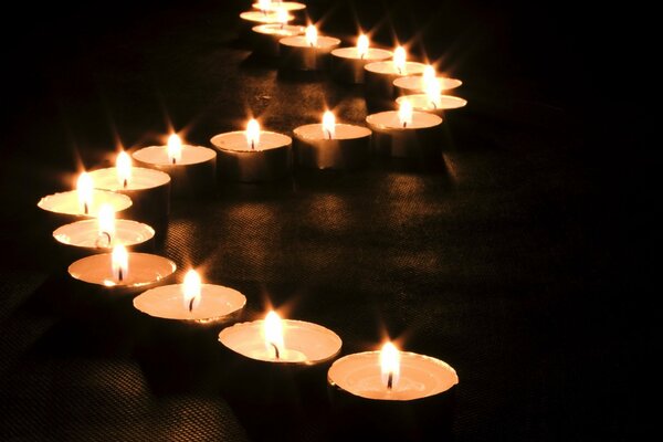 Las velas flotantes se componen en forma de onda se queman en la oscuridad