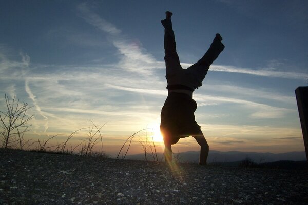 A man s somersault above the ground against the sky