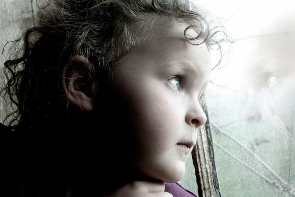 Reflection of a thoughtful child in the window