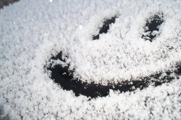 Cara sonriente pintada en un cristal cubierto de nieve