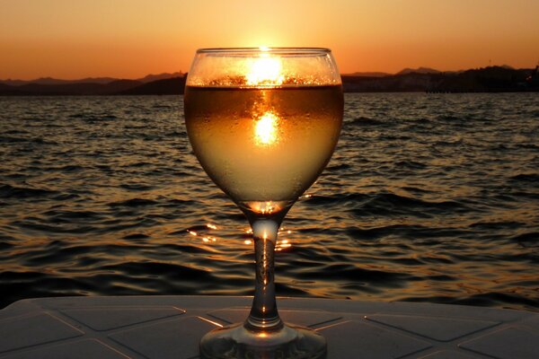 A glass of water on the background of the sea with sunset