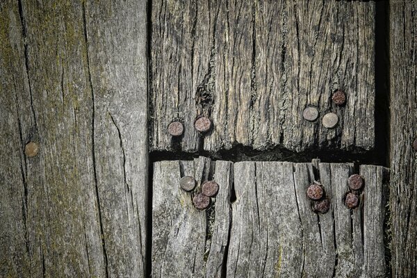 Holzbretter, auf denen rostige Nagelhüte zu sehen sind