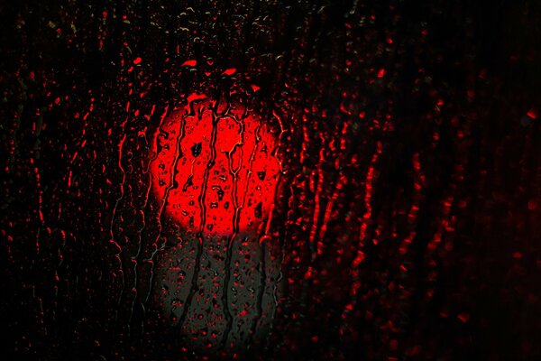 Red headlight through rainy glass