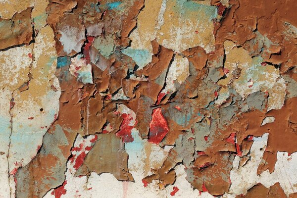 Layers of peeling colored paint on the wall