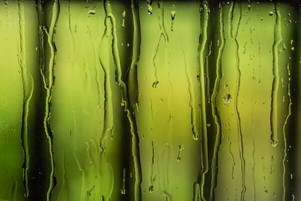 Water flows down the glass against the background of green lamps