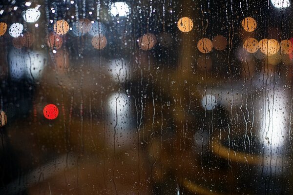 A través del cristal borroso de la lluvia se puede ver la ciudad nocturna