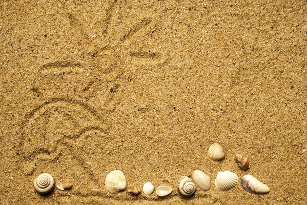 Bemalte Sonne auf Sand und Muscheln