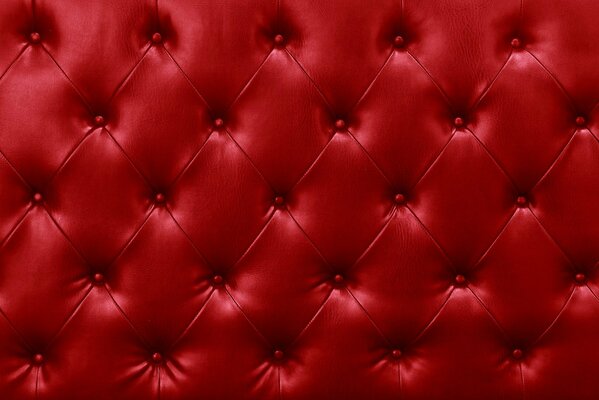 The texture of the upholstery of the red leather sofa