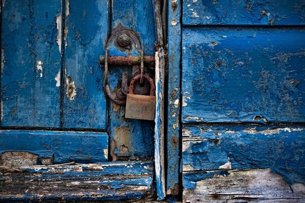 Das Schloss hängt an einer blauen Tür mit abgebrochener Farbe