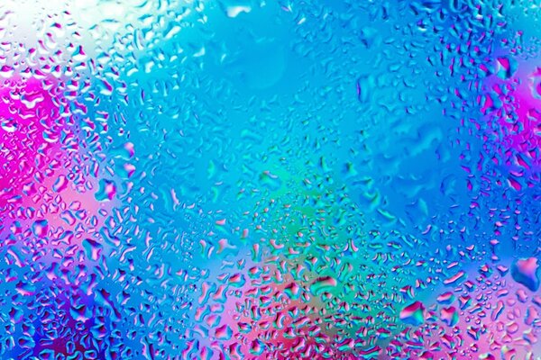 Gotas de agua en el vidrio sobre un fondo multicolor