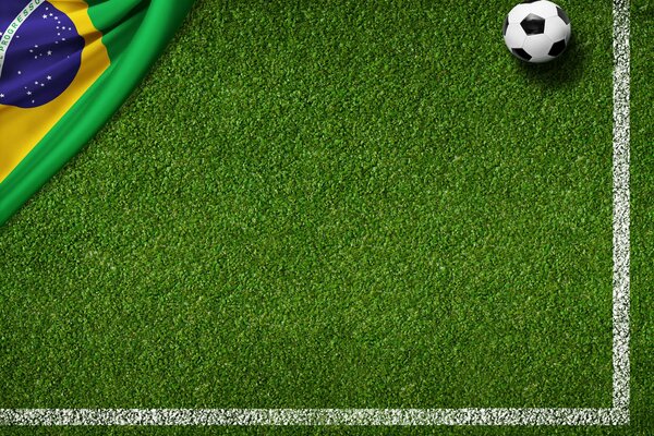 Piłka nożna i flaga Brazylii na trawniku