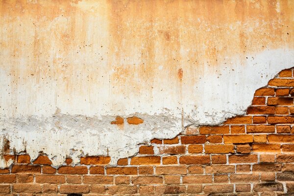 Stara ceglana ściana pokryta tynkiem nerwowym