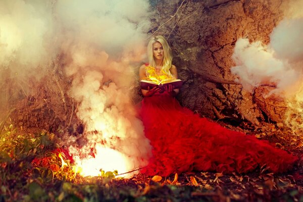 Ragazza con il libro nella foresta vicino al fuoco