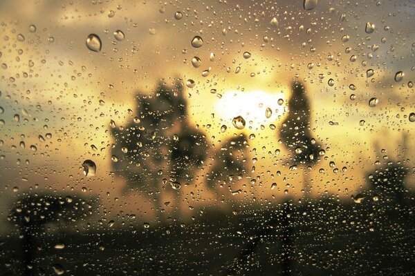 Sunset reflection through raindrops on glass