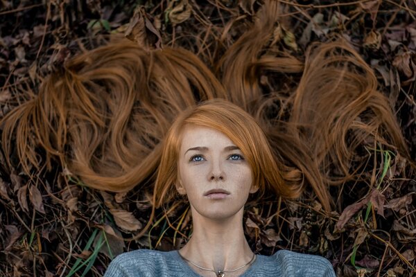 Retrato de una niña con el pelo rojo en el fondo de las hojas caídas