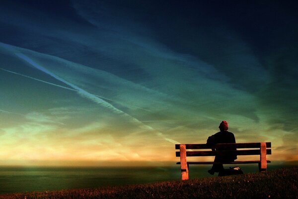 A lonely man on a bench against the background of the sky and the sea